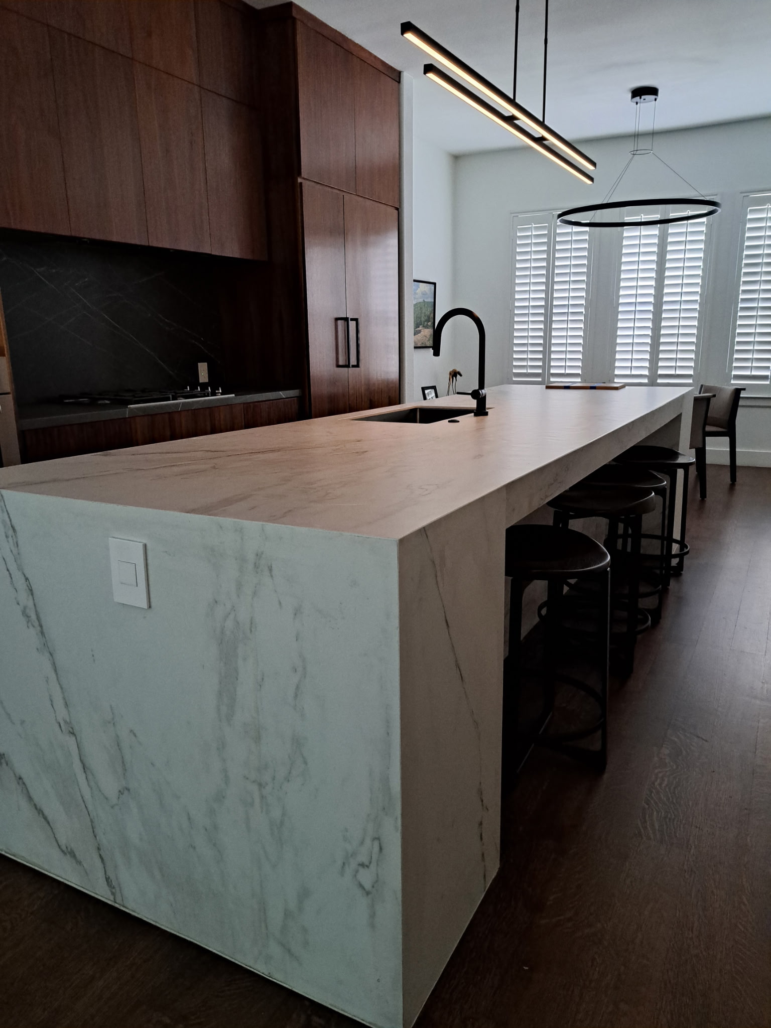 Modern custom kitchen with waterfall island and dark wood cabinetry